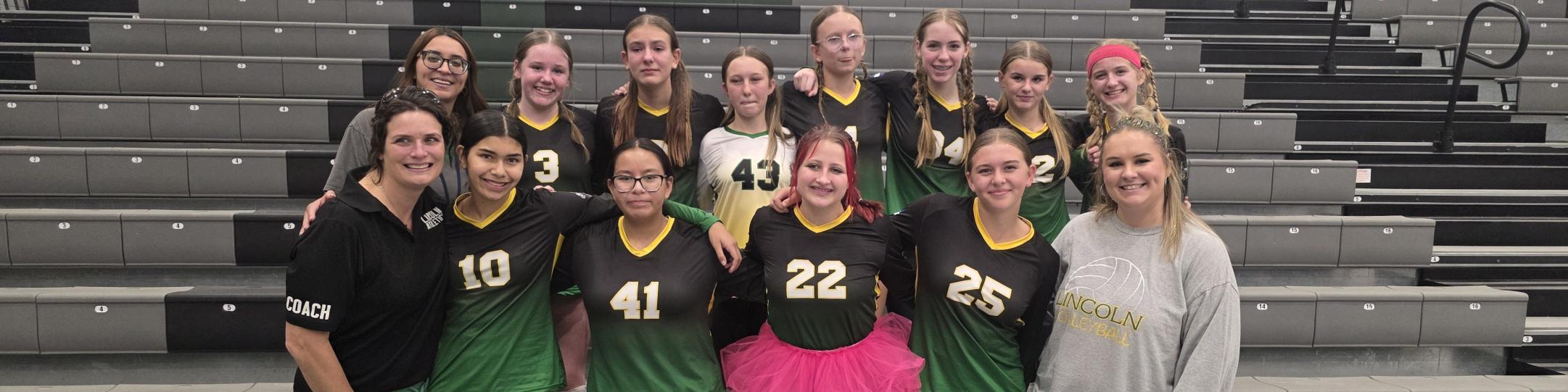 A group of girls and 2 women are smiling because they have just been crowned 3rd place champs in the Gold Bracket of the Volleyball Championships.