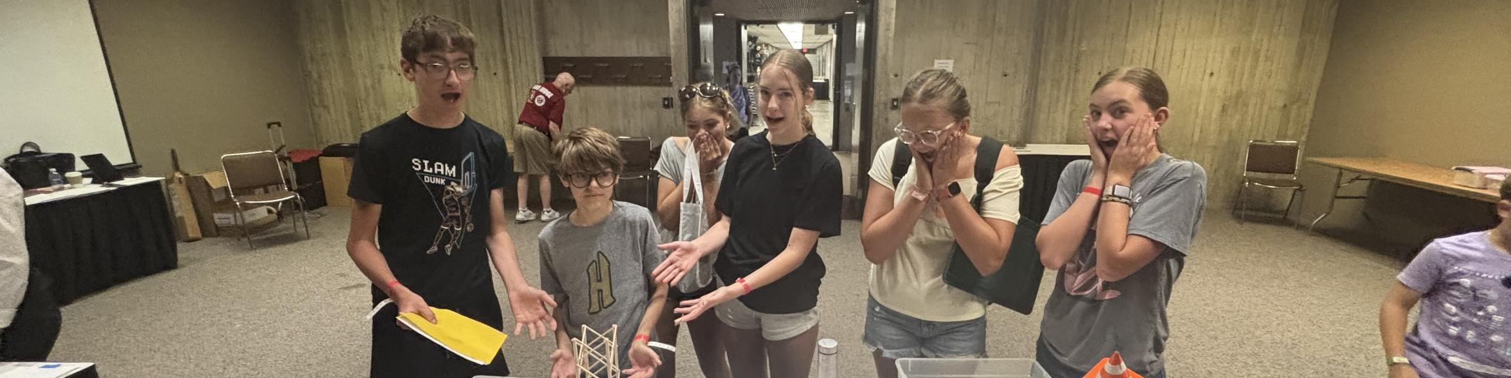 Studnets are presenting their solution to a problem at the Odyssey of the Mind World Competition. They are all excited, with their mouths open in amazement.