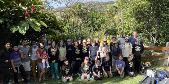 A group of students and adults pose in Costa Rica. Behind them is a view of the green, lush land. 