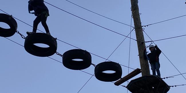 A kid is walking across tires suspended in the air 