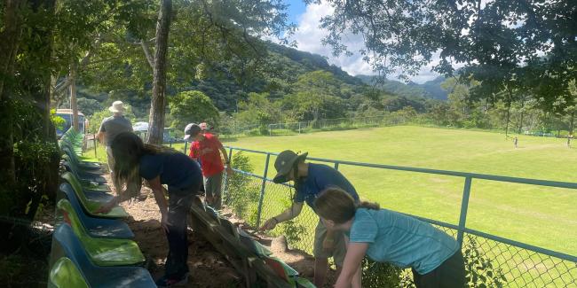 Students are painting stadium seats at an outdoor soccer field in Costa Rica.