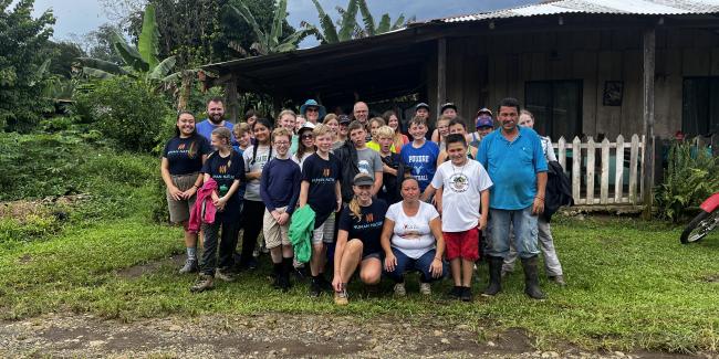 Students and adults standing a group posing for a picture. They are in Costa Rica 