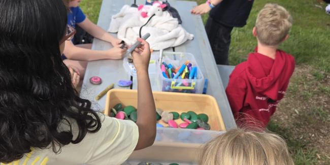 A group of middle school kids paint rocks at a park