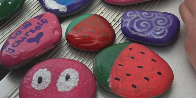 Rocks have been painted with faces, fruit and sayings