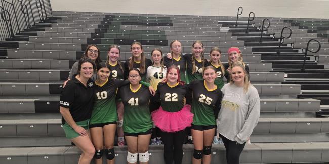 A group of girls and 2 women are smiling because they have just been crowned 3rd place champs in the Gold Bracket of the Volleyball Championships.