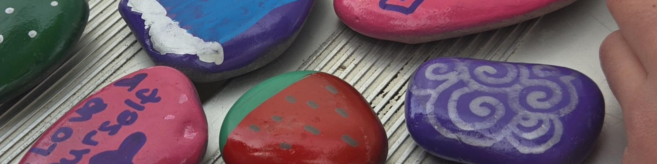 Rocks have been painted with faces, fruit and sayings