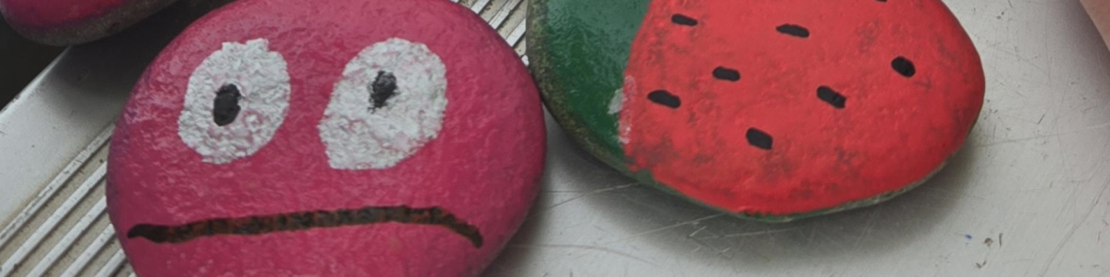 Rocks have been painted with faces, fruit and sayings