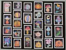 Art work from students is shown on a display board. Students drew pictures of nature with a twist. Most of the work contain mushroom or flower with a human eye incorporated into the image. 